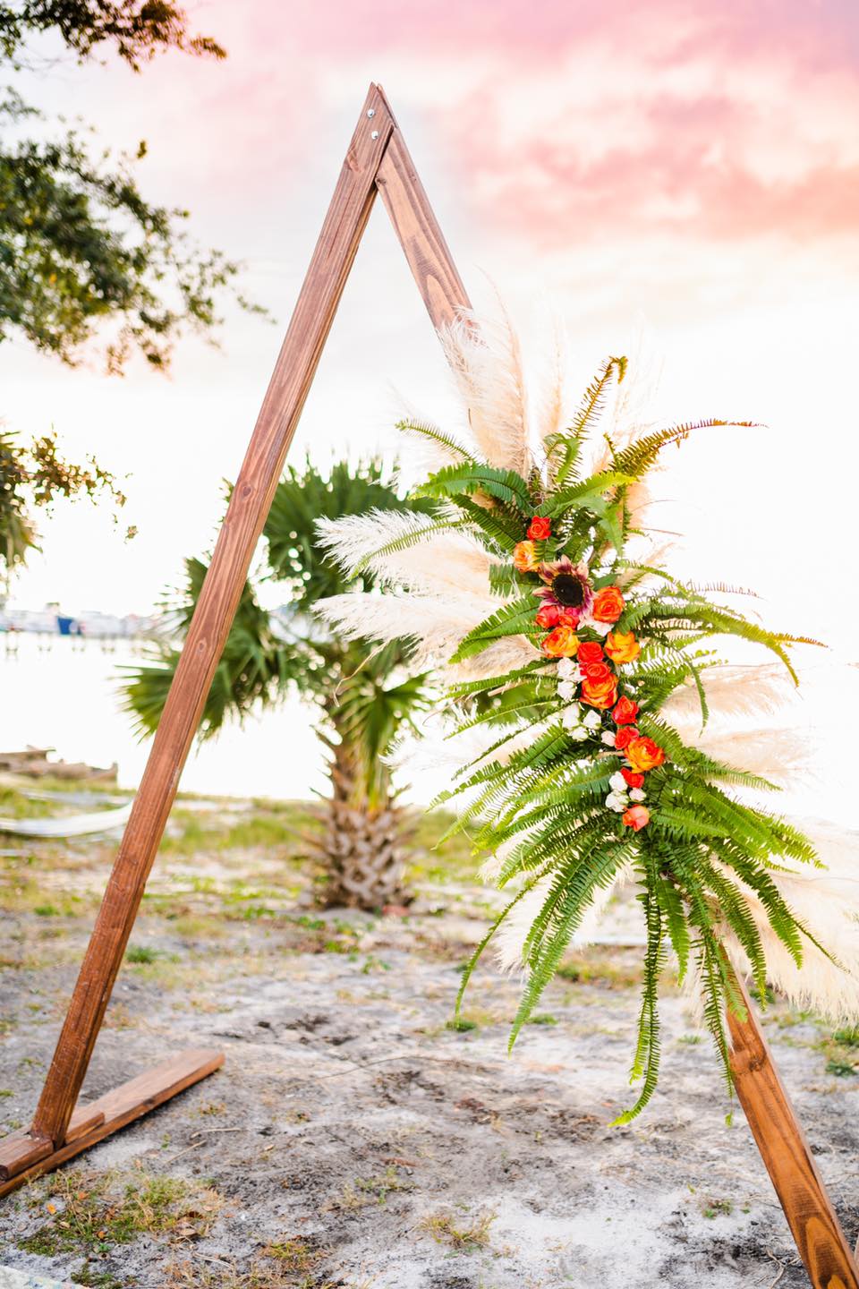 triable wooden wedding arch with tropical flowers attached