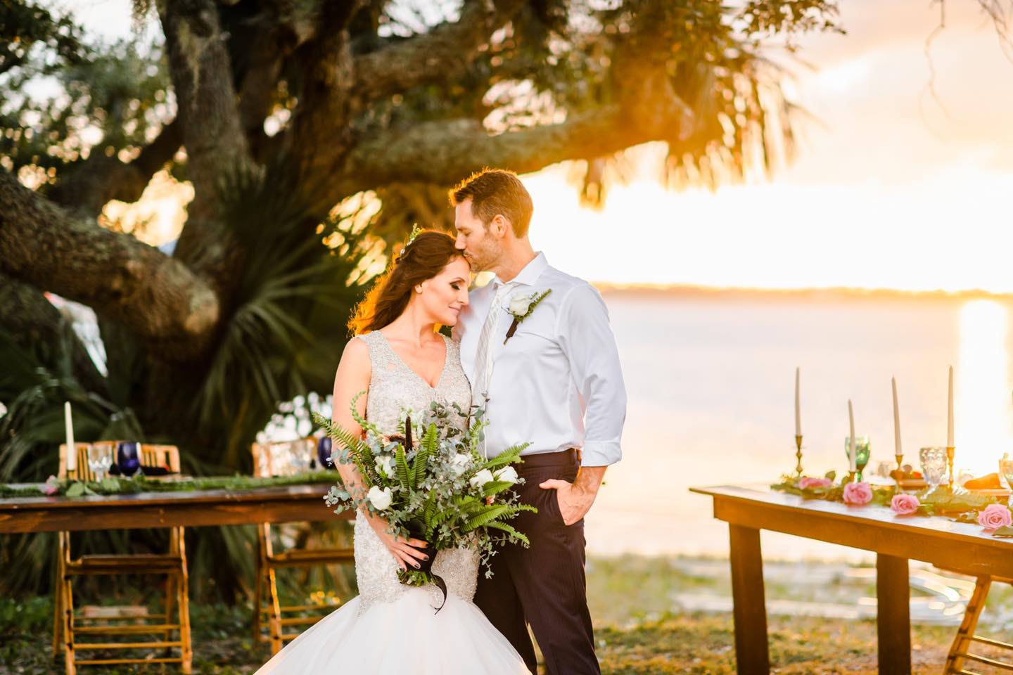 groom kissing bride on forehead at sunset
