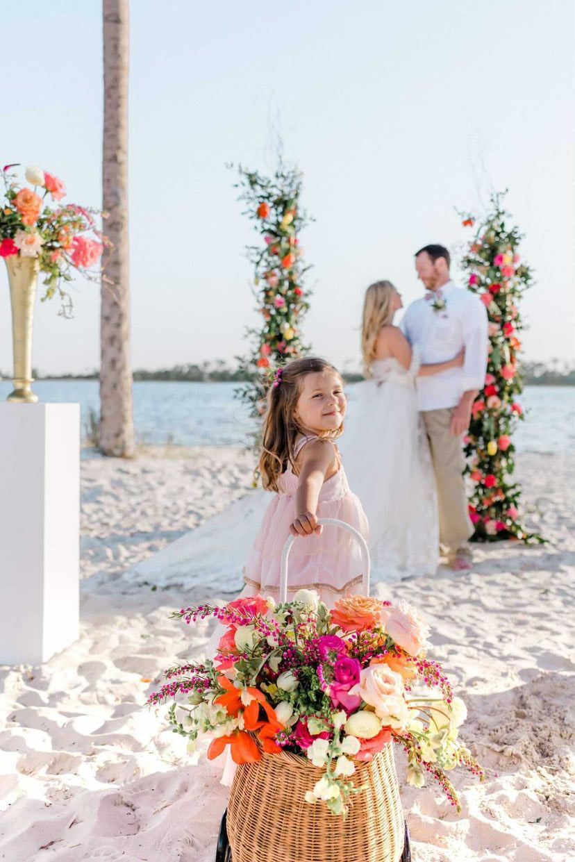 flower girl smiling while walking toward bride and groom